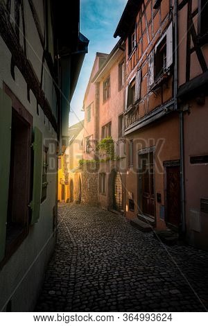 colorful halftimbered houses along a narrow street with cobblestones in the medieval town of Eguisheim, Alsace Region, France