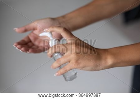 Close up view of woman person using small portable antibacterial hand sanitizer on hands. Stock photo