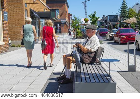 Magog, Qc, Canada - Aug. 20, 2022: Old Stylish Man Sitting On Rue Principale O Street In Downtown Ma