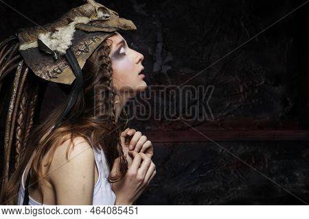 A Young Woman With Bright Make-up, Braided Hair And A Skull On Her Head Stands With Her Palms Folded