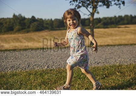 Charming Child In A Sundress Running Down The Street In The Suburbs