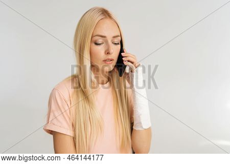 Close-up Portrait Of Worried Sad Young Woman With Broken Arm Wrapped In Plaster Bandage Talking Smar