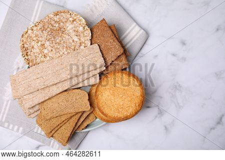 Rye Crispbreads, Rice Cakes And Rusks On White Marble Table, Flat Lay. Space For Text