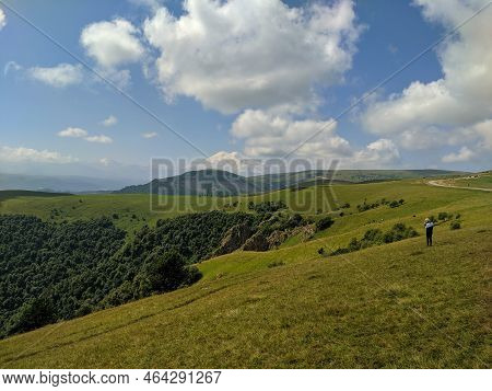 Beautiful View Of Elbrus In The Caucasus Mountains And Green Hills Against The Blue Sky. Prielbrusye