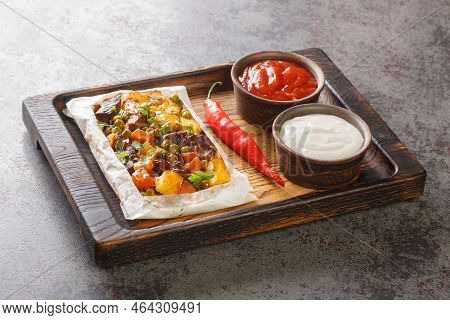 Turkish Kebab With Potatoes, Green Peas, Onions And Carrots Wrapped In Paper And Baked Close-up On A