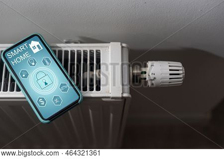 Smartphone With Launched Application For Air Temperature Adjustment Opposite The Radiator. Health Mi