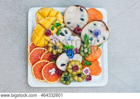 Flat Lay Of Exotic Tropical Fruits. Gold Kiwi, Persimone, Raspberry, Mango, Oranges And Mint. Plate 