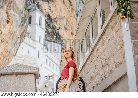 Woman Tourist In Monastery Of Ostrog, Serbian Orthodox Church Situated Against A Vertical Background