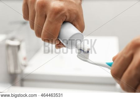 Man Applying Toothpaste On Brush In Bathroom, Closeup