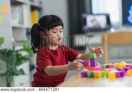 Asian Cute Funny Preschooler Little Girl In A Colorful Shirt Playing With Lego Or Construction Toy B