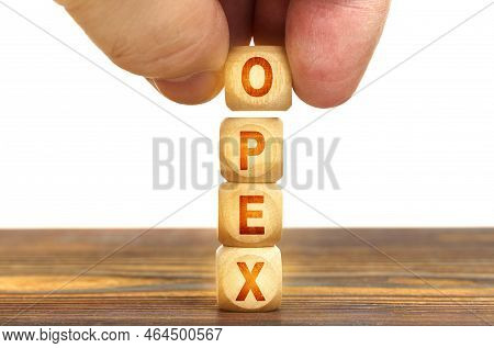 Business Concept. A Man Puts Wooden Cubes On The Table With The Inscription - Opex