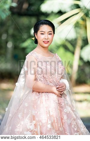 Asian Girl In An Old Rose Pink Color Knee Length Fluffy Dress With High Heel Slingback Shoes And Cer