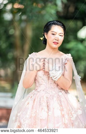 Asian Girl In An Old Rose Pink Color Knee Length Fluffy Dress With High Heel Slingback Shoes And Cer
