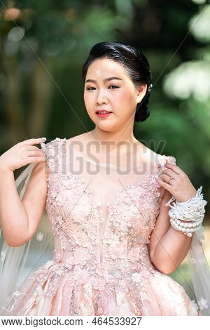 Asian Girl In An Old Rose Pink Color Knee Length Fluffy Dress With High Heel Slingback Shoes And Cer