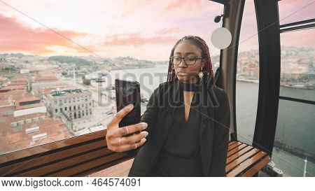 Portrait Of A Cute Young Black Female Tourist In The Car Of A Ropeway Taking A Selfie On Her Cellpho