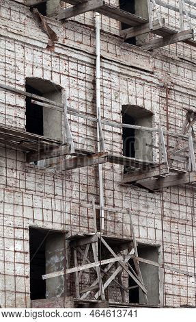 Brick Wall Of Old Destroyed House Without Windows With Wooden Broken Scaffold. Abandoned Repair Of U
