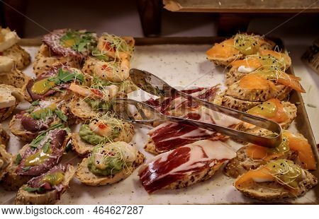 Many Tapas, Small Baguettes Pieces With Toppings On A Board.