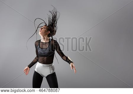Fit Woman In Futuristic Bodycon Jumpsuit And Silver Shorts Posing With Dreadlocks On Wind Isolated O