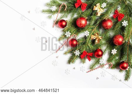 Christmas Tree Branch Decorated With Christmas Balls, Bows, Snowflakes And Candy Canes On A White Ba