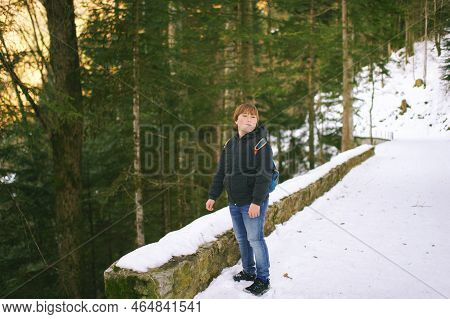 Outdoor Portrait Of Cuty Kid Hiking In Winter Forest, Young Boy Wearing Backback Hiking In Mountains