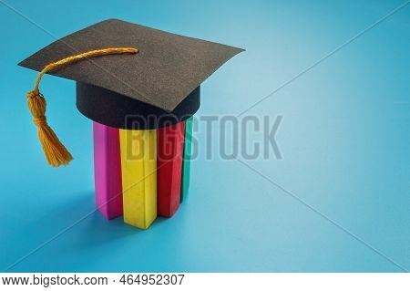 Inclusion And Neurodiversity Education. Colored Crayons On Which A Graduation Cap Is Worn.