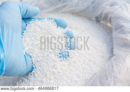 Hand In Blue Glove Holds White Fertilizer For Plants. Big Bag With Chemical Npk Fertilizer For Plant