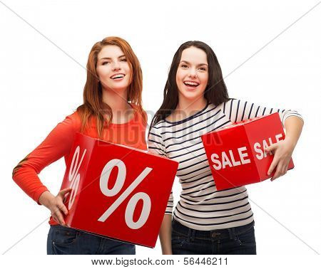 shopping, sale, and gift sconcept - two smiling teenage girls with percent and sale sign on red box