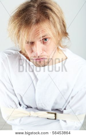 Mentally ill man in strait-jacket on gray background