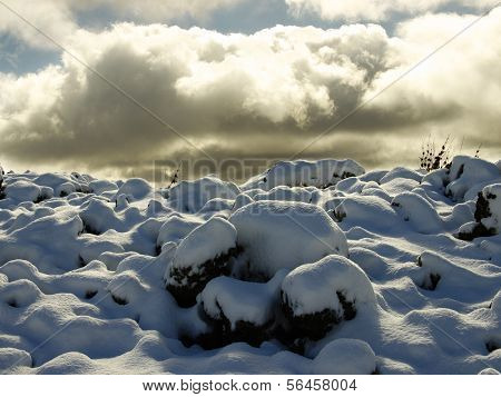 cold lava covered by snow on background clouds  
