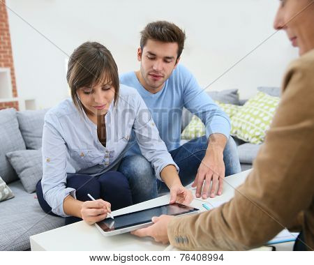 Young couple signing financial contrat on digital tablet