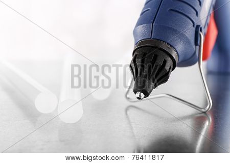 Dark blue glue gun and silicone stick on light background