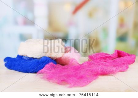 Multicolored wool for felting on table on bright background