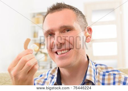 Man showing deaf aid in ear