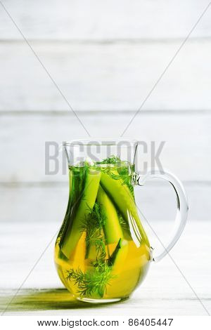 Glass ewer with fresh organic cucumber water on wooden table