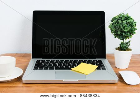 Laptop And Flower Pot On Wooden Table