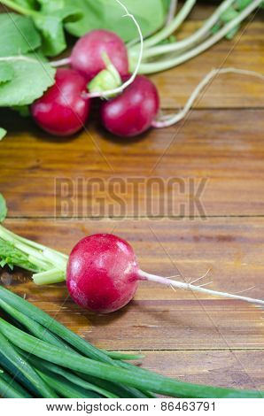 Raw Radishes And Young Onion On A Wooden Table