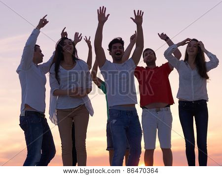 group of happy young people dancing and have fun on party in modern home bacony with sunset and ocean in background