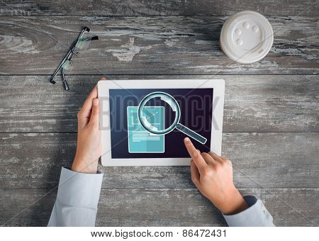 business, people, statistics and technology concept - close up of hands pointing finger to tablet pc computer screen showing magnifier and graph on table