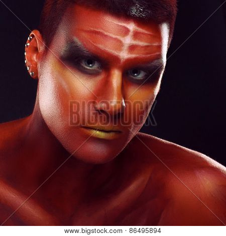 Portrait of a handsome young man in a red body painting