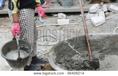 Constrution work put water on concrete mixing tray in building site