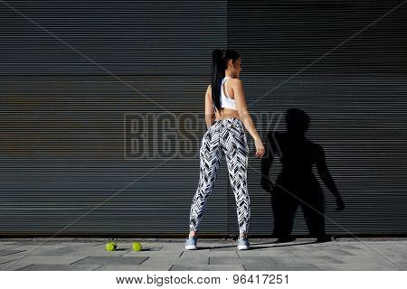 Woman with perfect figure and buttocks taking break against wall with copy space for your text