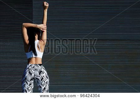 Cropped back view portrait of sporty woman with perfect figure and buttocks stretching her arms