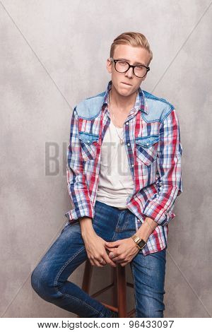 Young man hoding his hands together while sitting on a chiar.