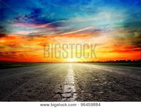 Asphalt road between fields  trees 