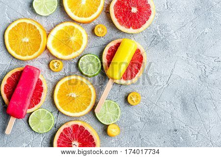 fresh citrus slices with fruit popsicles on stone table background top view mock up