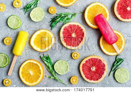 homemade citrus popsicles with fresh fruit slices on stone table background top view pattern