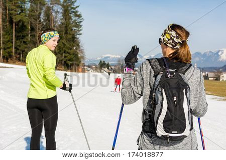 Pair of skiiers taking a break and talking. Cross country skiing.