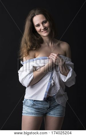 Closeup portrait of young brunette woman in white shirt, dark studio wall background