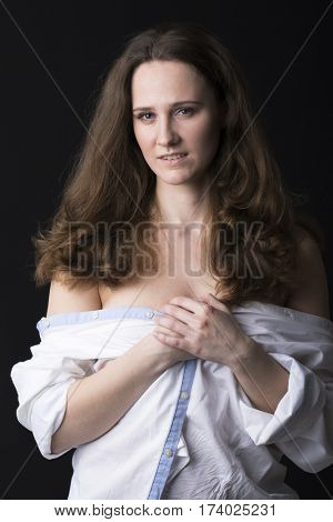 Closeup portrait of young brunette woman in white shirt, dark studio wall background