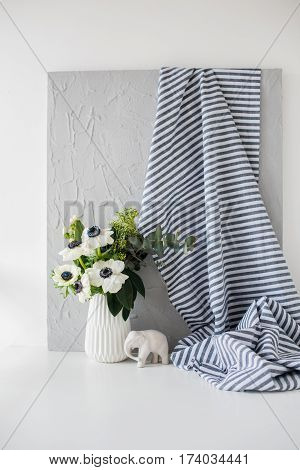 Still-life with an elegant bouquet of anemones in a vase on table in white room interior, floral home dcoration